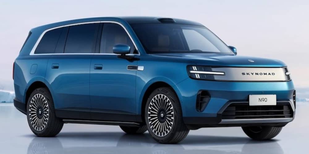 Ein blaues SUV der Marke Skynomad (Modell N90) steht vor einer verschneiten Kulisse. Das Fahrzeug zeichnet sich durch schmale LED-Scheinwerfer, ein Kennzeichen mit dem Schriftzug „N90“ und auffällige Speichenfelgen aus.