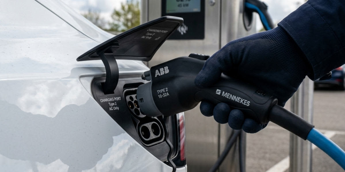 Aus einer Zapfpistole an einer Tankstelle fließt Kraftstoff. In der vergrößerten, hängenden Sprit-Träne ist eine 1-Euro-Münze als Symbol für die Kraftstoffpreise zu sehen.