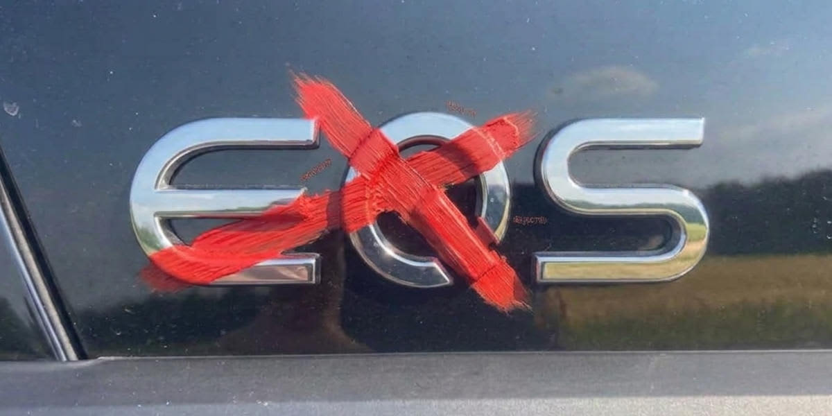 Auf dem Heck eines schwarzen Autos ist der verchromte „EQS“-Schriftzug zu sehen, wobei die Buchstaben „EQ“ mit roter Farbe durchgestrichen wurden.