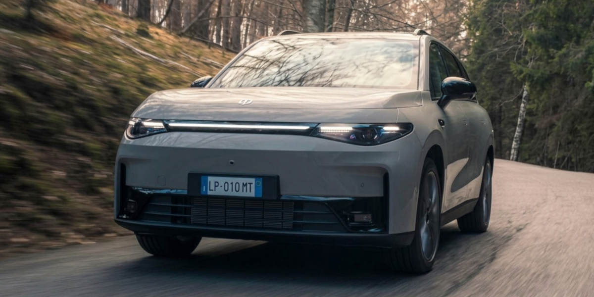 Ein grauer Leapmotor C10 fährt auf einer Waldstraße. Prägend sind das durchgehende LED-Lichtband an der Front und die smarte SUV-Proportion.   