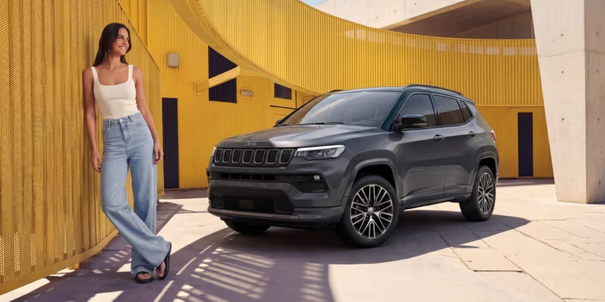 Jeep Compass Summit vor einer gelben Wand. Frau steht angelehnt an der Wand