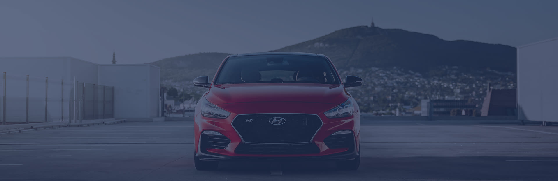 Ein roter Hyundai in der Frontansicht steht auf einem leeren Parkplatz