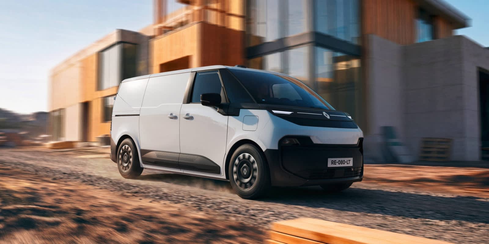 Ein weiß-schwarzer Renault Flexis Elektro-Transporter fährt an modernen Gebäudefronten vorbei. Prägend ist das zukunftsweisende Van-Design.