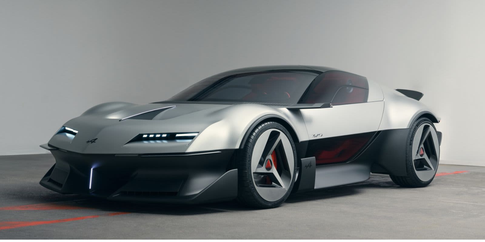 Ein silberner Alpine A310 Concept steht in einem hellen Studio. Auffällig sind die flache Sportwagen-Silhouette, schmale LED-Lichter und dreieckige Felgenelemente.