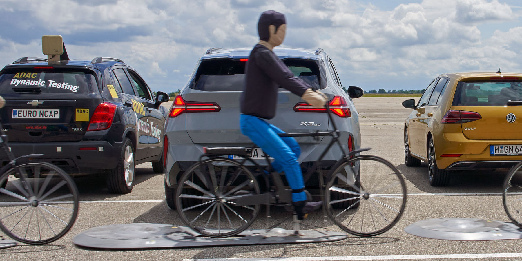 Crashdummy auf Fahrrad hinter einem Auto
