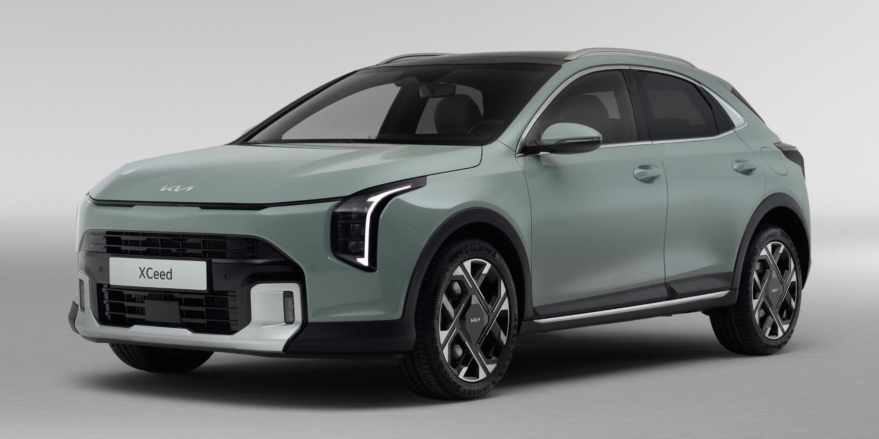 Ein mintgrüner Kia XCeed Crossover mit schwarzem Dach, markant geschwungenen LED-Scheinwerfern und zweifarbigen Felgen steht schräg vor einem neutralen, hellgrauen Studiohintergrund.