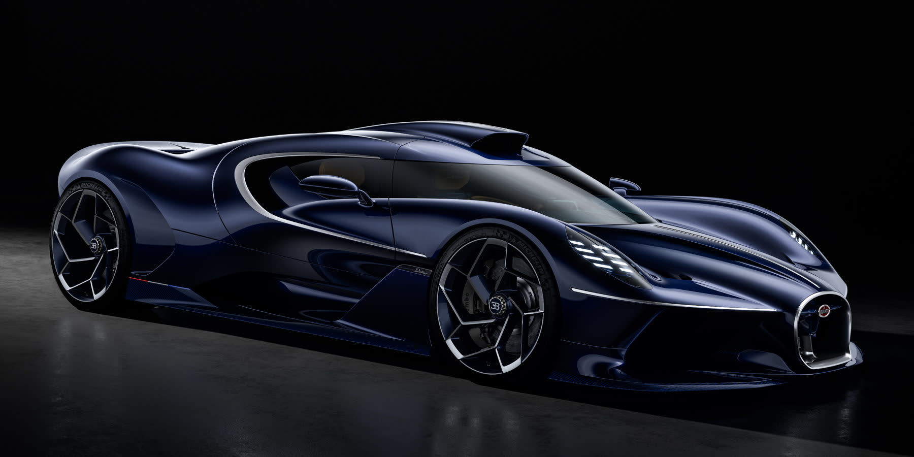 Ein dunkelblauer Bugatti Sportwagen präsentiert sich vor einem schwarzen Hintergrund mit markanter Lufthutze auf dem Dach und auffälligen Alufelgen.
