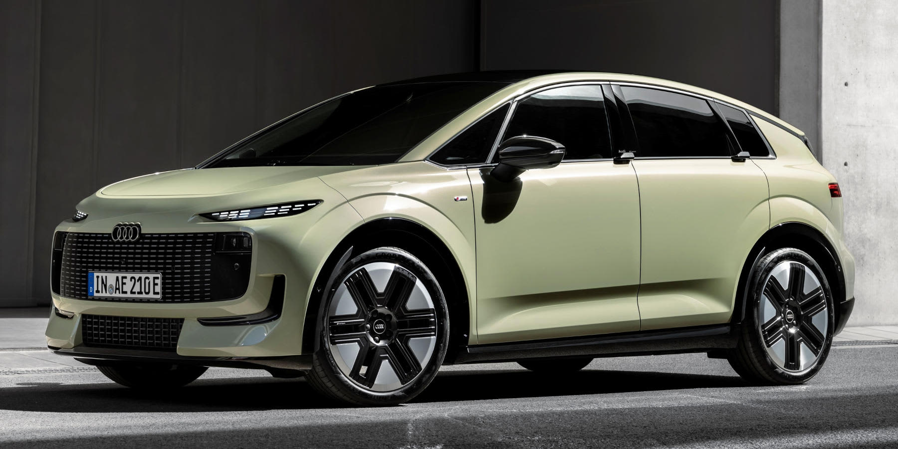 Ein hellgrüner Audi A2 e-tron steht seitlich vor grauer Kulisse. Auffällig sind die schlanken LED-Lichter und das aerodynamische Design.
