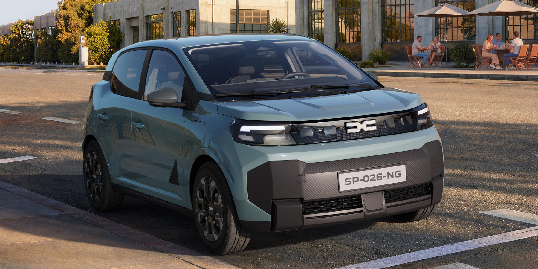Ein hellblauer Dacia Spring Kleinwagen steht auf einer städtischen Straße vor einem Straßencafé. Auffällig ist die Y-förmige Lichtsignatur.