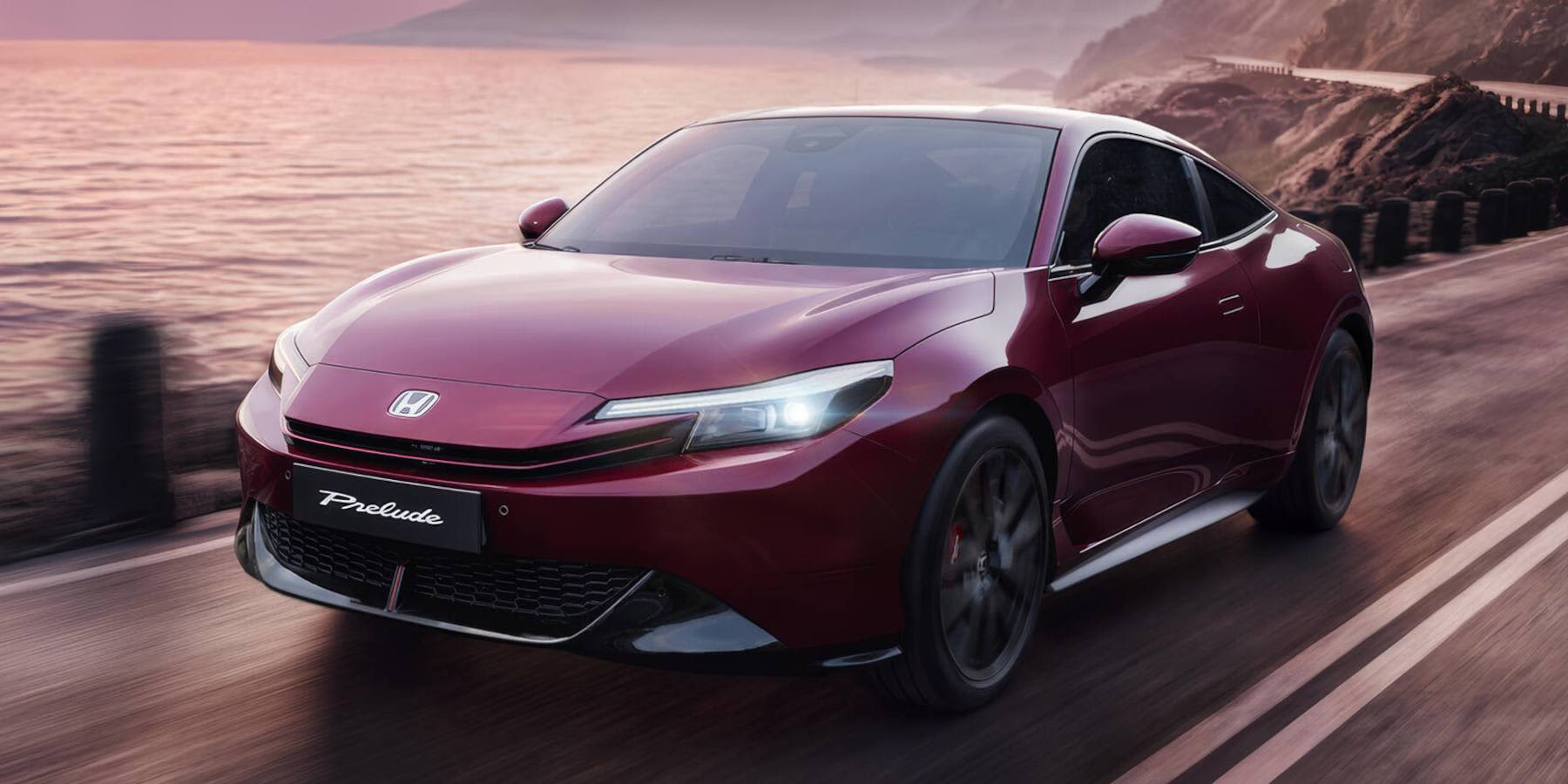 Ein weinroter Honda Prelude fährt bei Abendlicht auf einer Küstenstraße. Das Design zeichnet sich durch schmale LED-Scheinwerfer und eine elegante Coupé-Linie aus.   