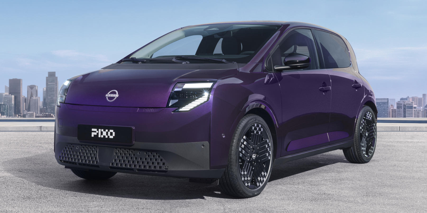 Ein violetter Nissan Pixo steht auf einer Freifläche vor einer Skyline. Markant sind die modernen LED-Scheinwerfer und die auffälligen Felgen.