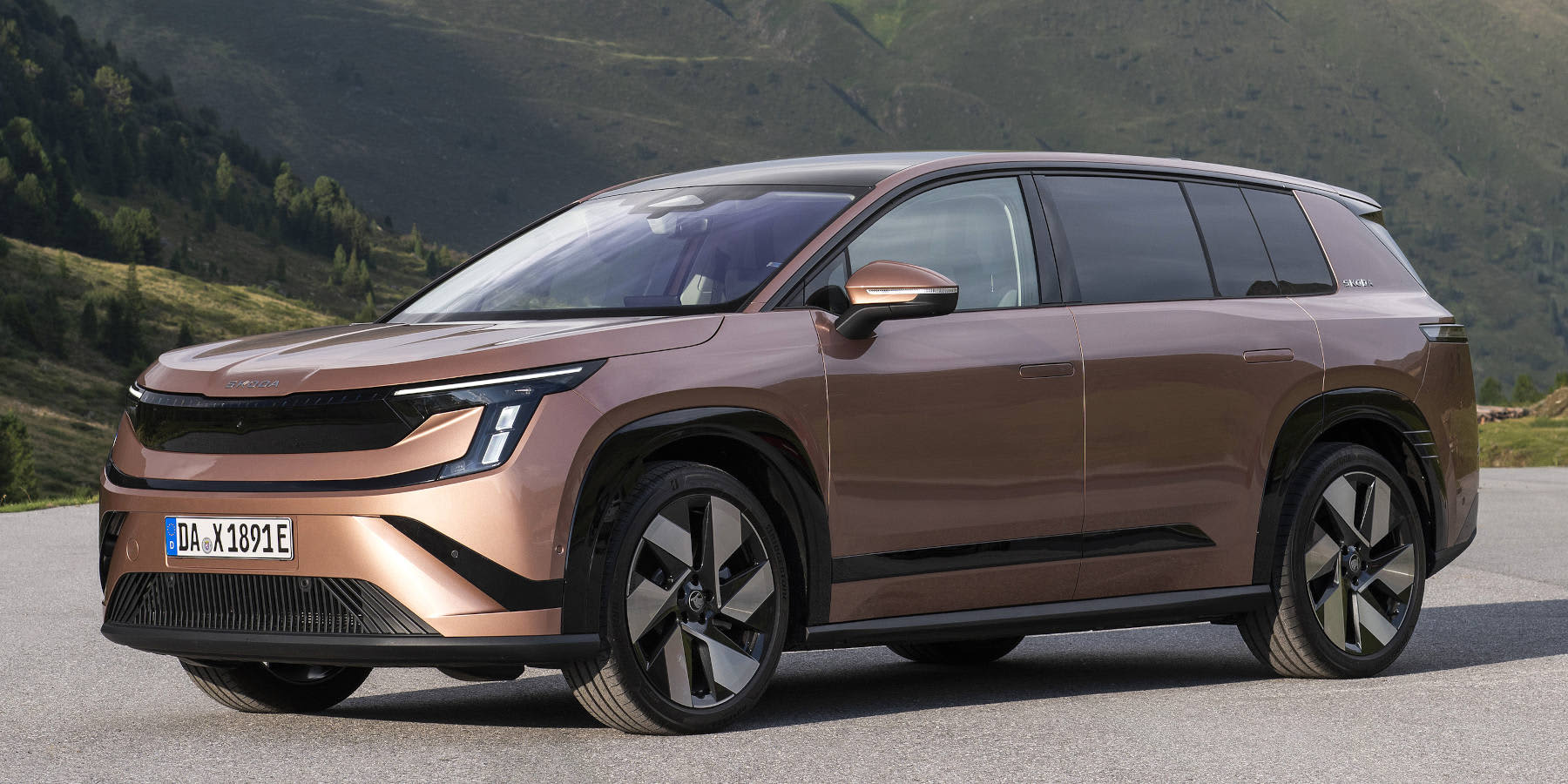 Ein bronzefarbener Skoda Peaq Elektro-SUV steht vor einer Bergkulisse. Prägend sind die schmalen LED-Scheinwerfer und das Modern-Solid-Design.