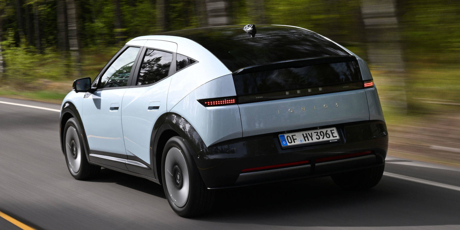 Hyundai Ioniq 3 in hellblauer Lackierung während der Fahrt von hinten.