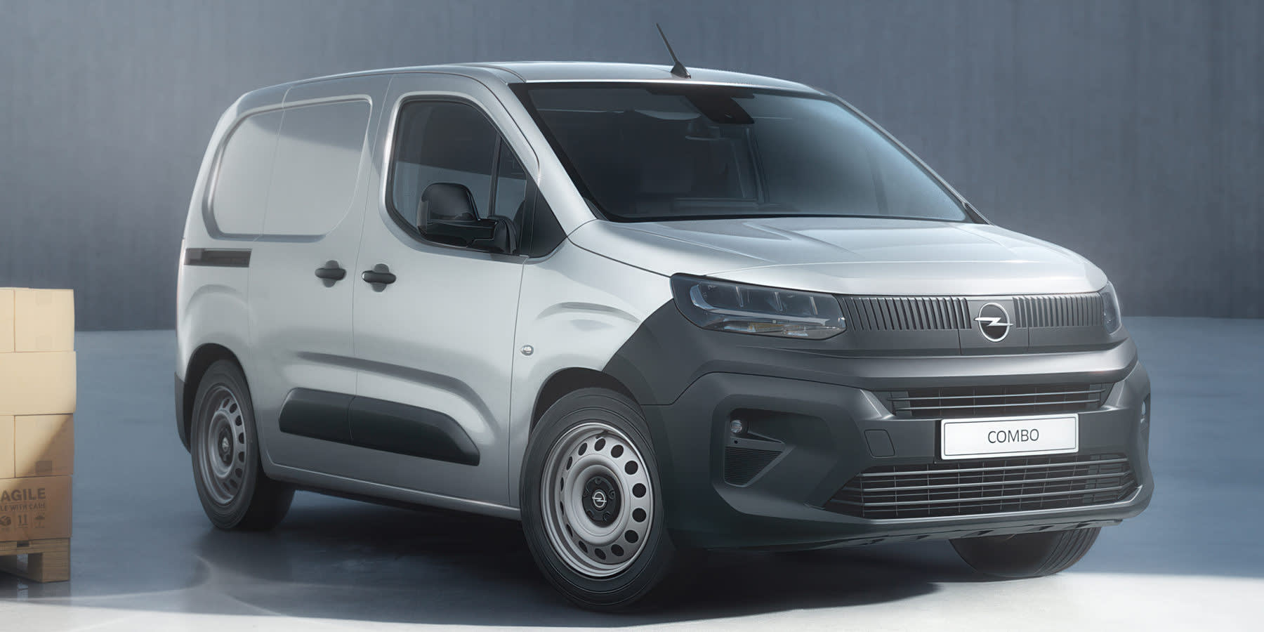 Ein silberner Opel Combo Kastenwagen steht im Studio vor gestapelten Kartons. Markant ist die schwarze Vizor-Frontpartie.