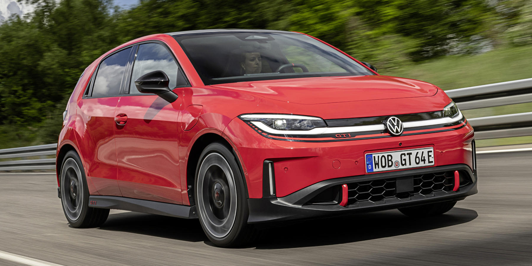Ein roter Volkswagen ID. Polo GTI fährt dynamisch auf einer Rennstrecke. Prägend sind roter GTI-Akzente, das LED-Lichtband und die kompakte Hot-Hatch-Form.   