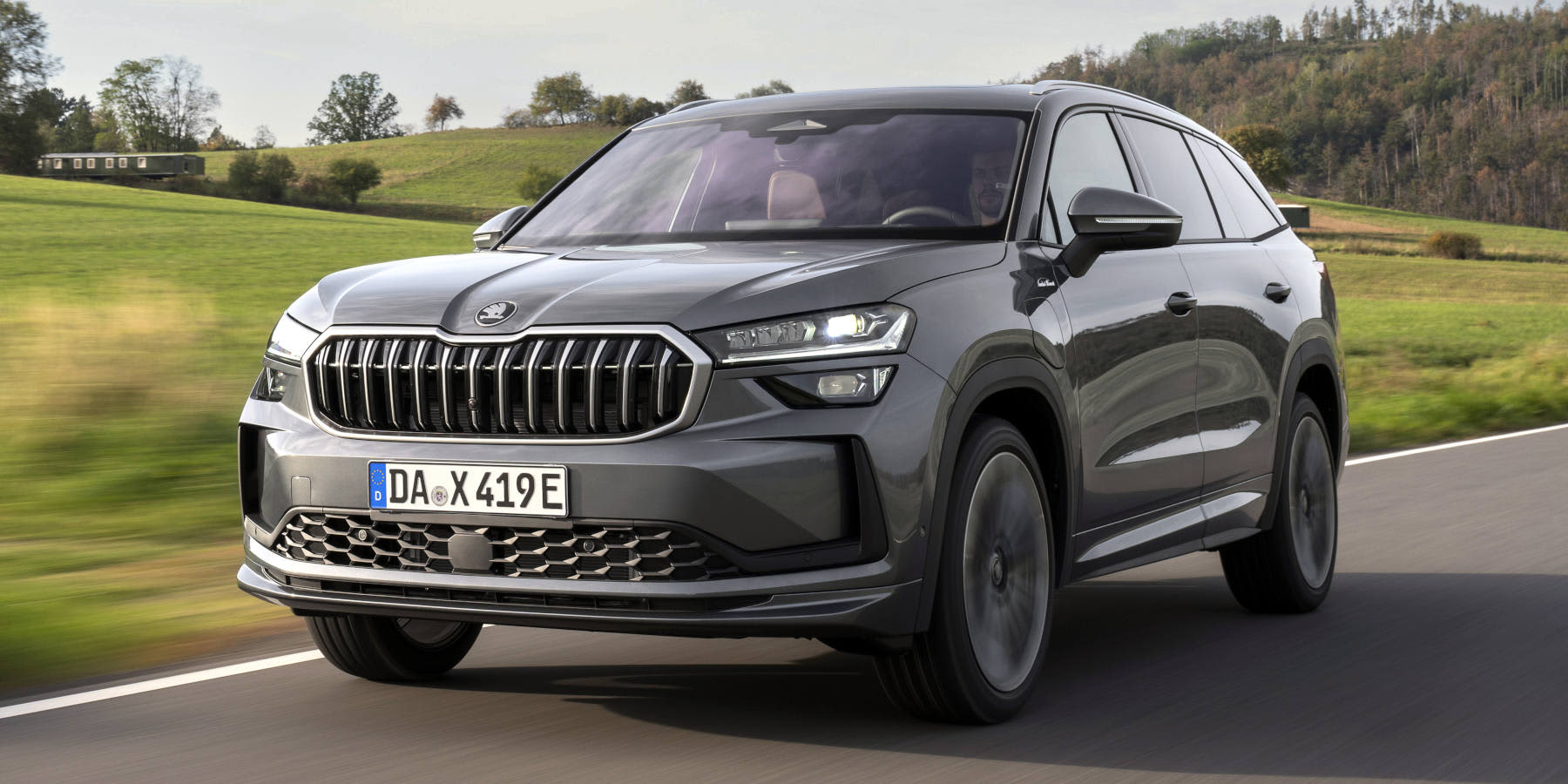 Grauer Skoda Kodiaq fahrend von vorne auf einer Straße.