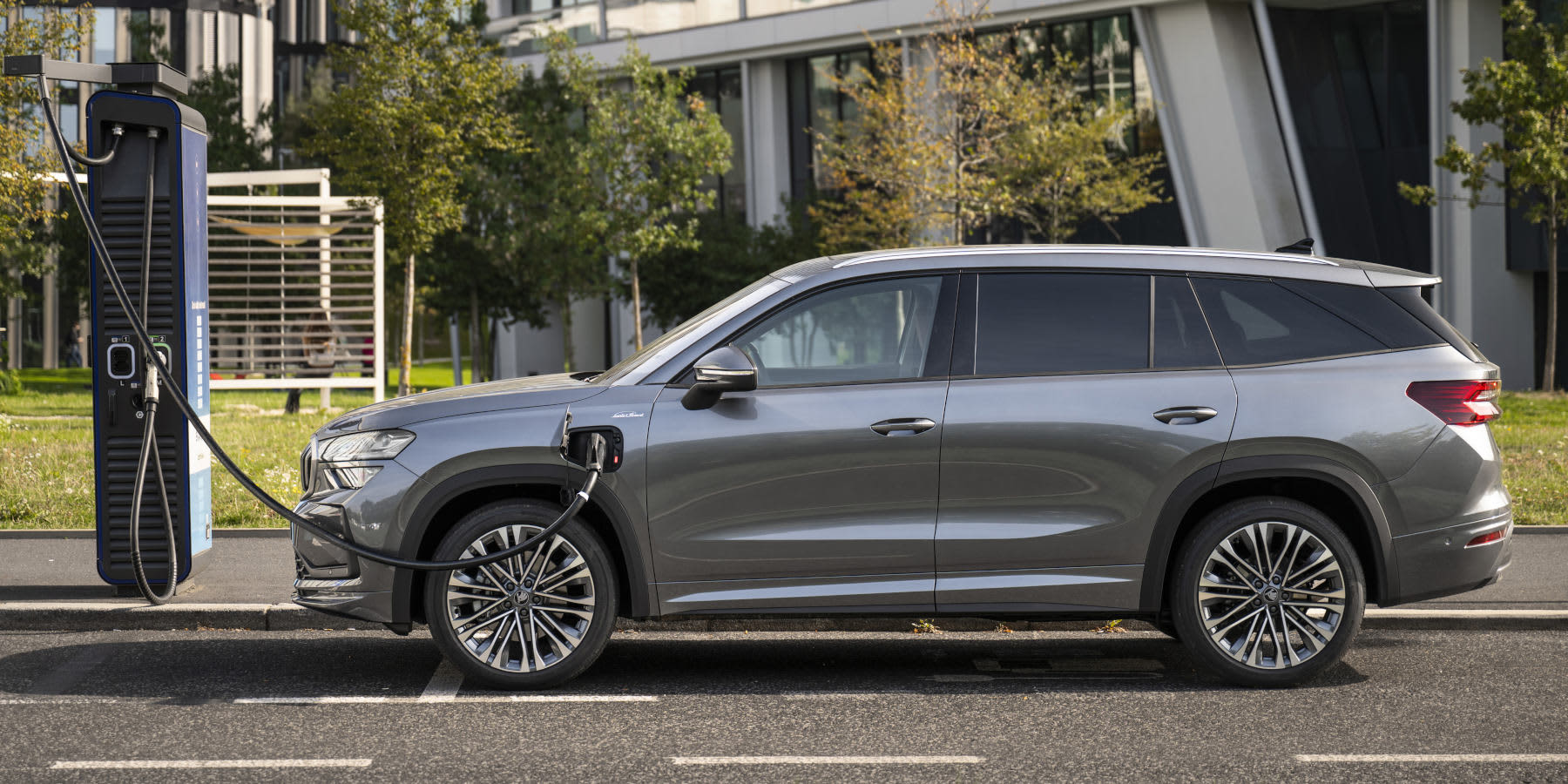 Grauer Skoda Kodiaq ladend seitlich.