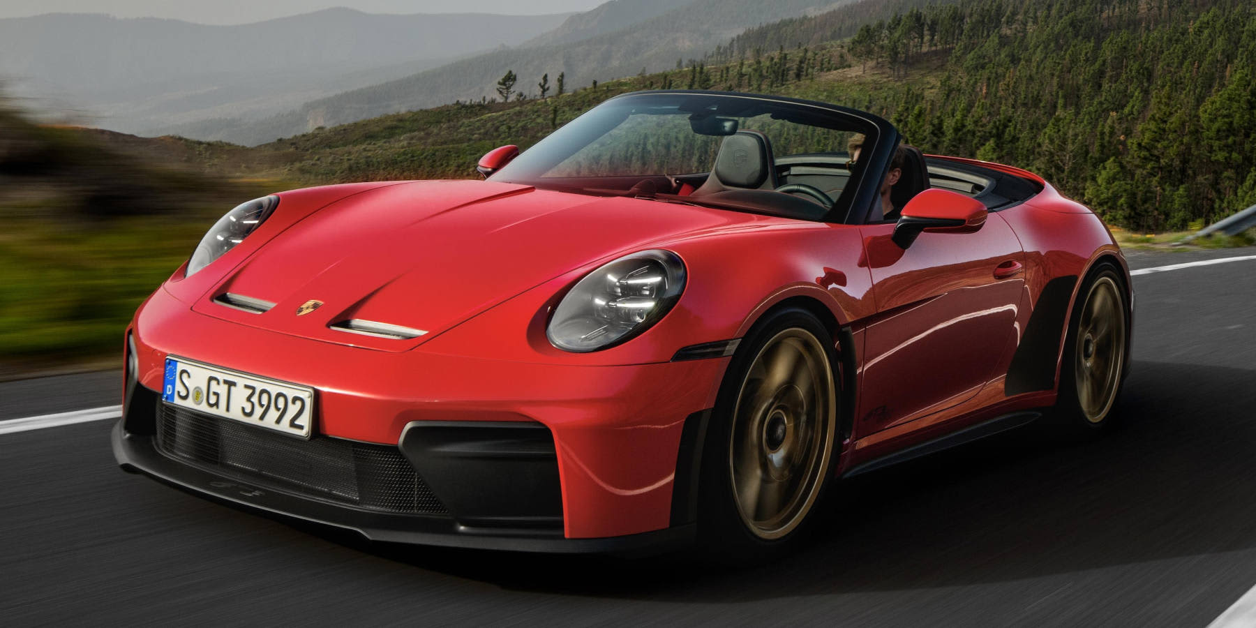 Roter Porsche 911 GT3 S/C fährt auf einer Straße mit offenem Verdeck