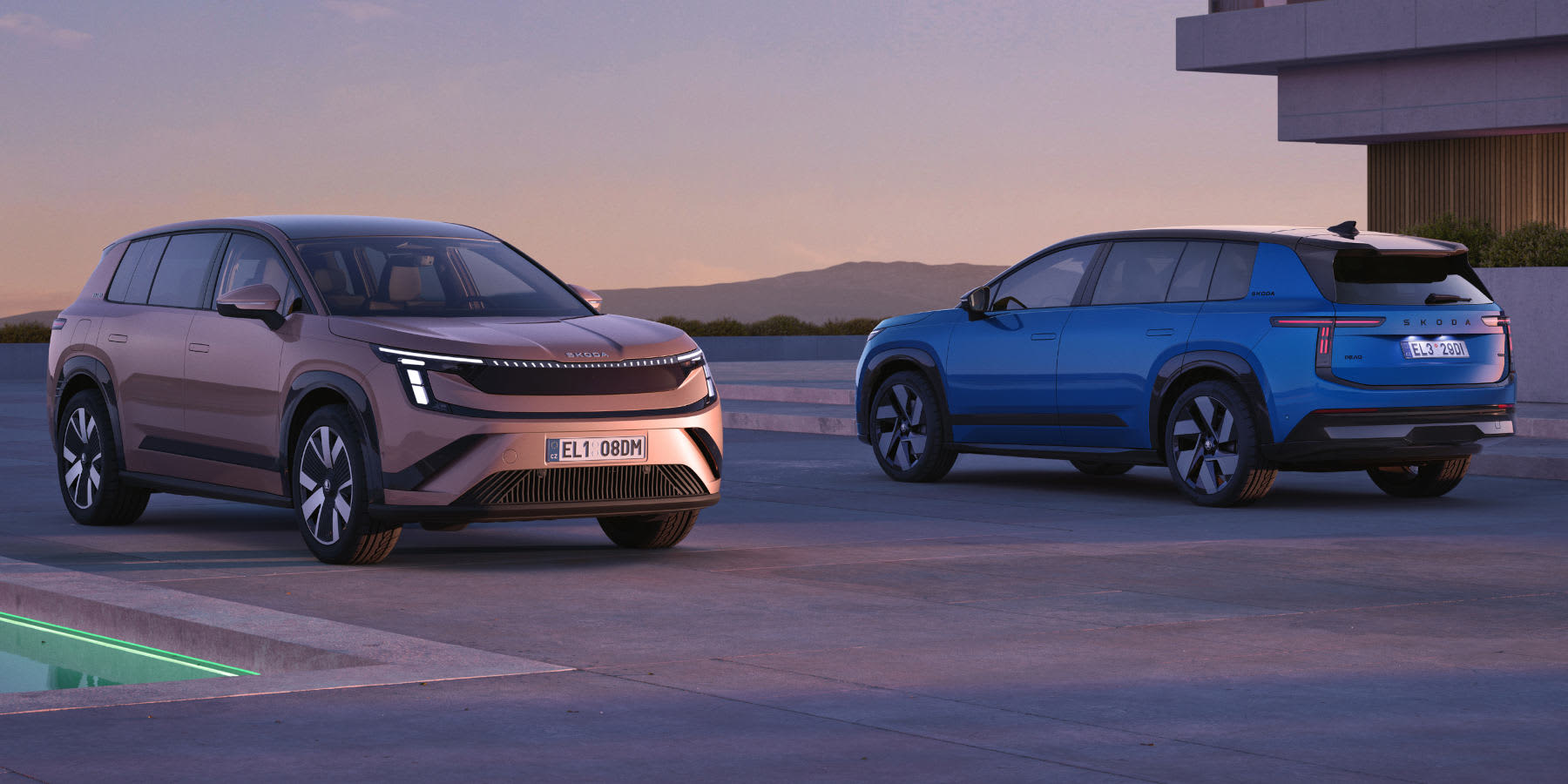 Zwei Skoda Peaq SUVs bei Dämmerung. Links steht ein bronzefarbenes Modell von vorne mit durchgehendem LED-Lichtband, rechts ein blaues Modell mit schwarzem Dach von schräg hinten. Beide Fahrzeuge haben tschechische Kennzeichen.