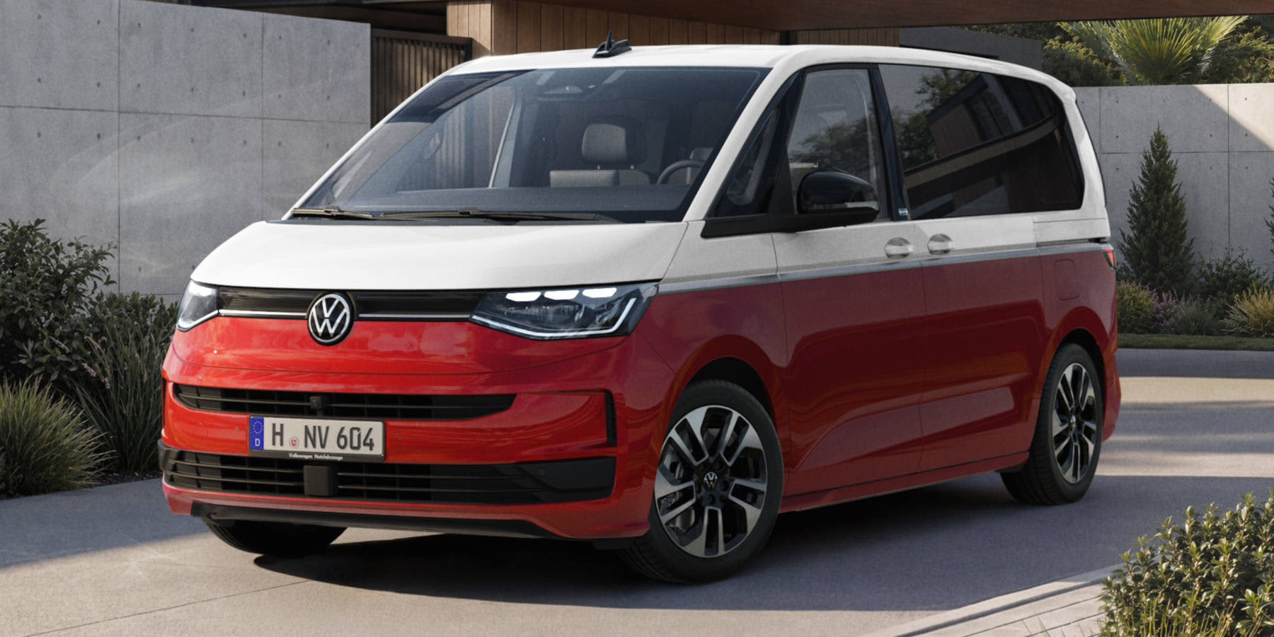 Ein rot-weißer VW Multivan steht auf einer Einfahrt vor einem modernen Haus. Der Van in klassischer Zweifarblackierung hat zweifarbige Alufelgen und ein Hannoveraner Kennzeichen (H NV 604).