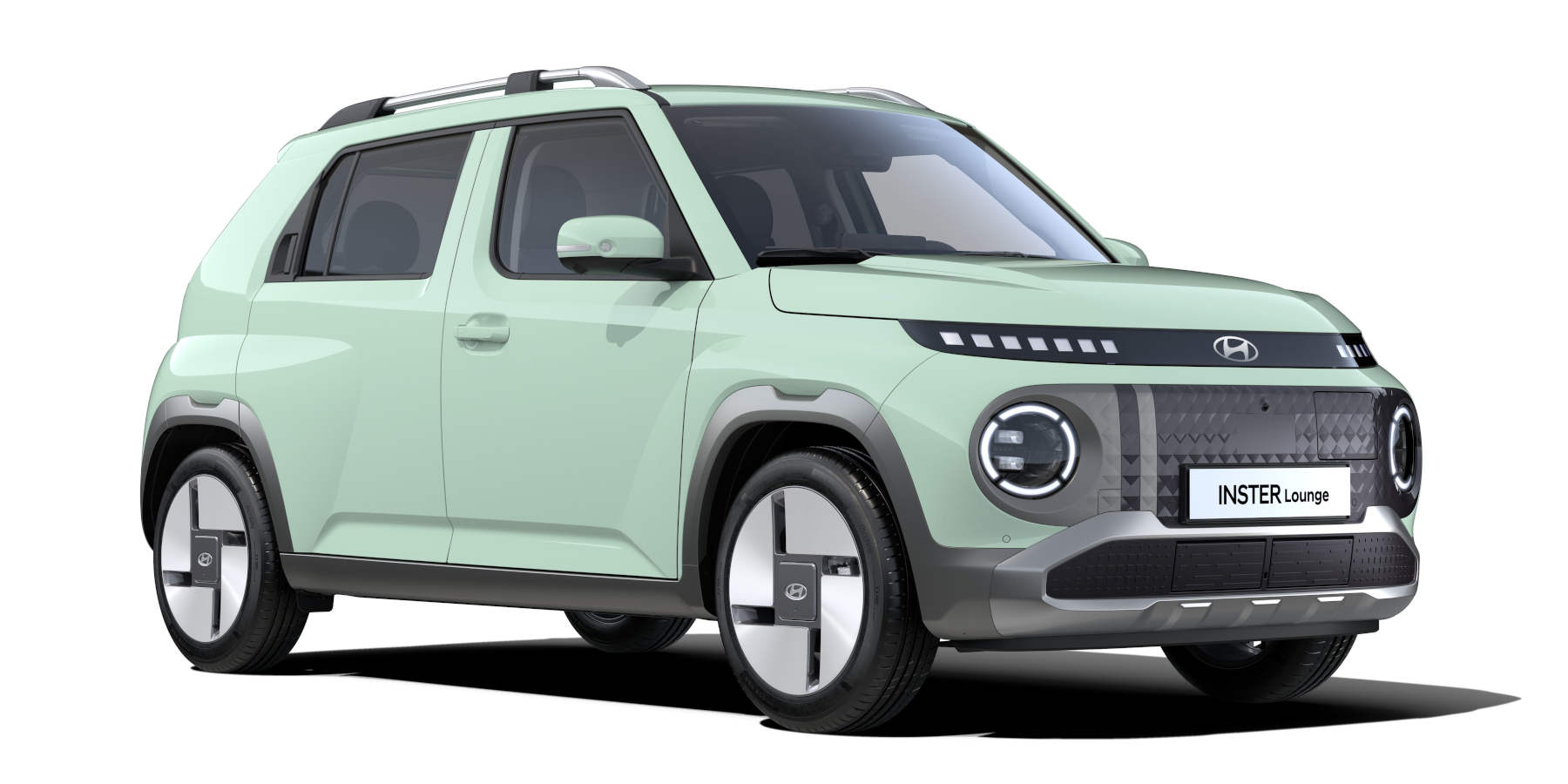 Schrägansicht eines hellgrünen Hyundai Inster Lounge vor weißem Hintergrund. Das kompakte Elektro-SUV zeichnet sich durch runde Scheinwerfer mit LED-Ringen, eine verpixelte LED-Leiste an der Front und auffällige, flächige Felgen aus.