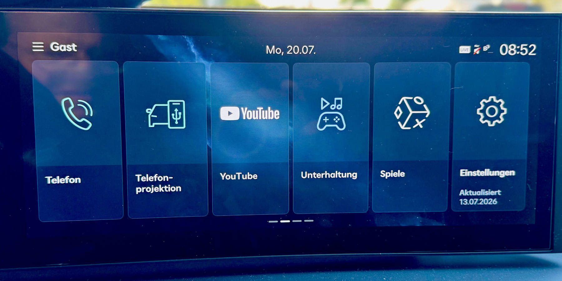 Das Infotainmentsystem eines Autos zeigt ein blaues Menü mit Kacheln wie „Telefon“, „YouTube“, „Unterhaltung“ und „Einstellungen“. (KI-generiert)