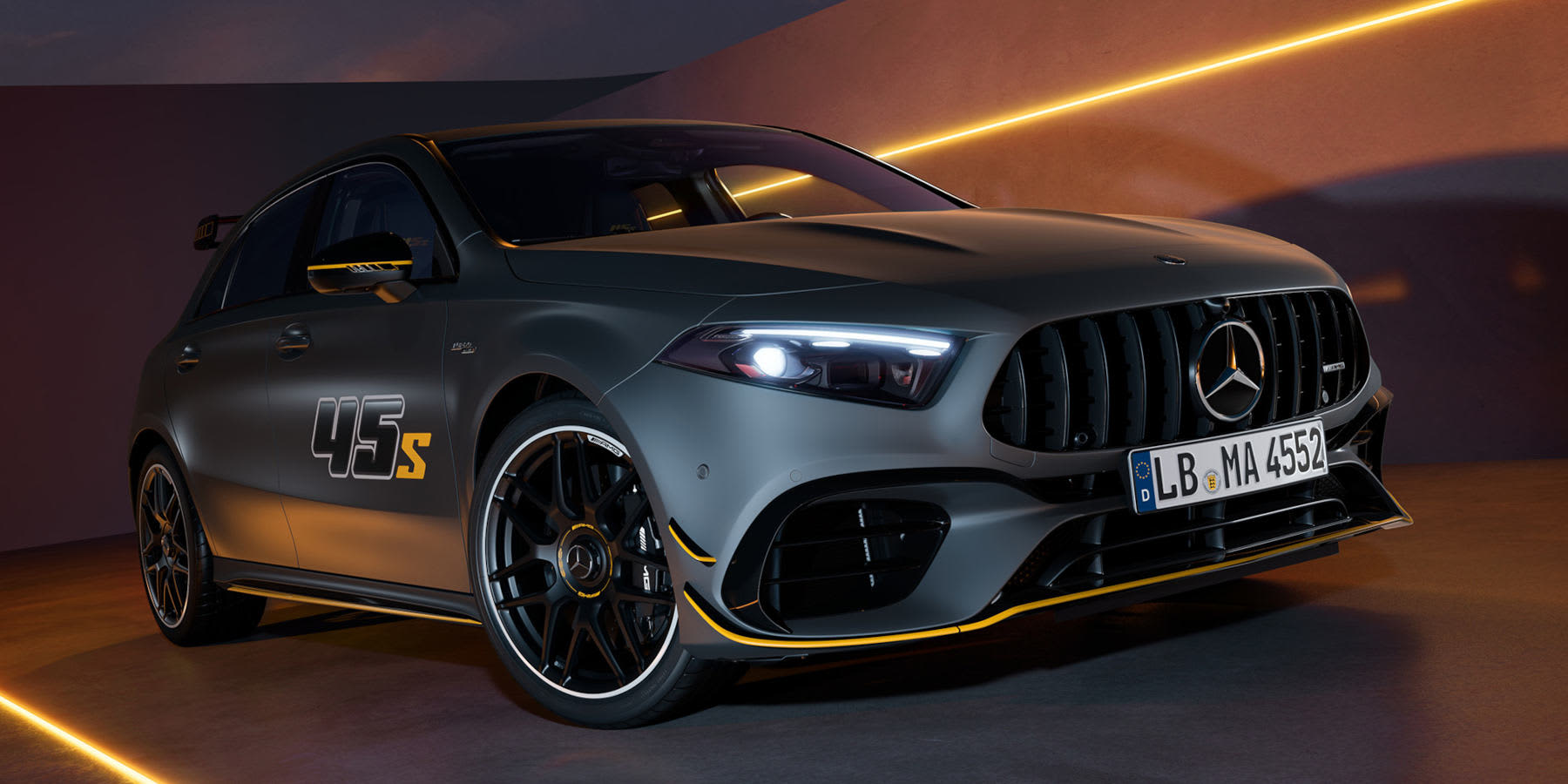 Ein mattdunkelgrauer Mercedes-AMG A 45 S der Final Edition steht in einer modern ausgeleuchteten Kulisse. Das sportliche Fahrzeug hebt sich durch gelbe Zierleisten, einen auffälligen „45 S“-Schriftzug an den Türen ab. (KI-generiert)