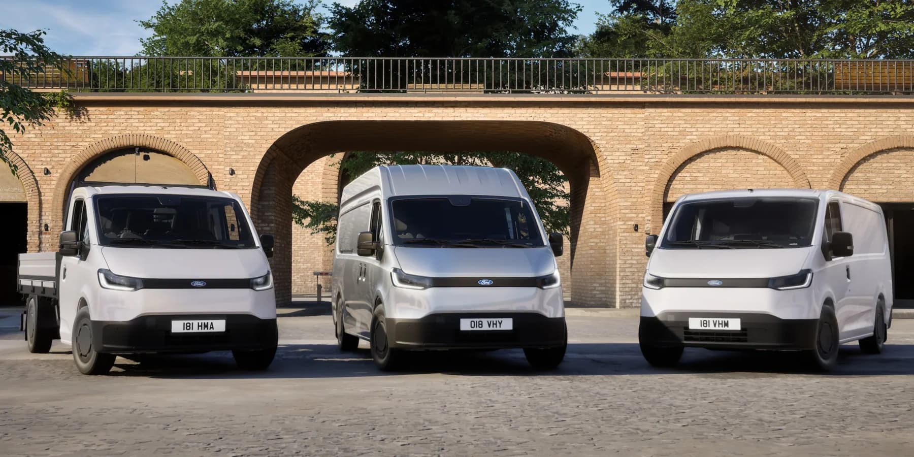 Drei weiße Ford Transit Elektro-Transporter stehen nebeneinander vor Backsteinbögen: eine Pritsche, ein Hochdach-Kastenwagen und ein Standard-Transporter. (KI-generiert)