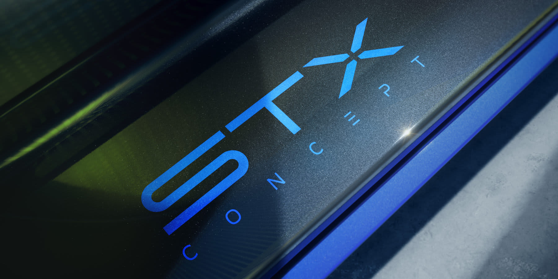 Ein beleuchteter, blauer „STX CONCEPT“-Schriftzug ist auf dunkler Oberfläche abgebildet. Prägend sind die moderne Typografie und der leuchtende Farbverlauf.    (KI-generiert)