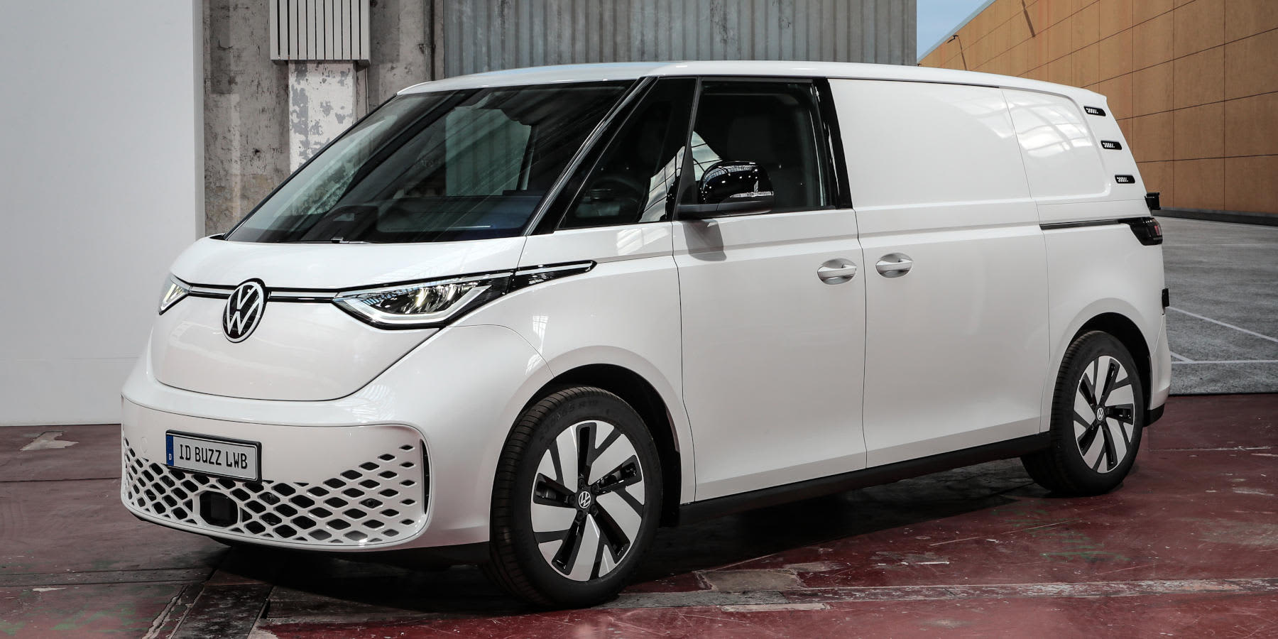 Ein weißer VW ID. Buzz Cargo LWB steht in einer Halle. Prägend sind der verlängerte Radstand, die geschlossenen Seitenwände und das LED-Lichtband. (KI-generiert)