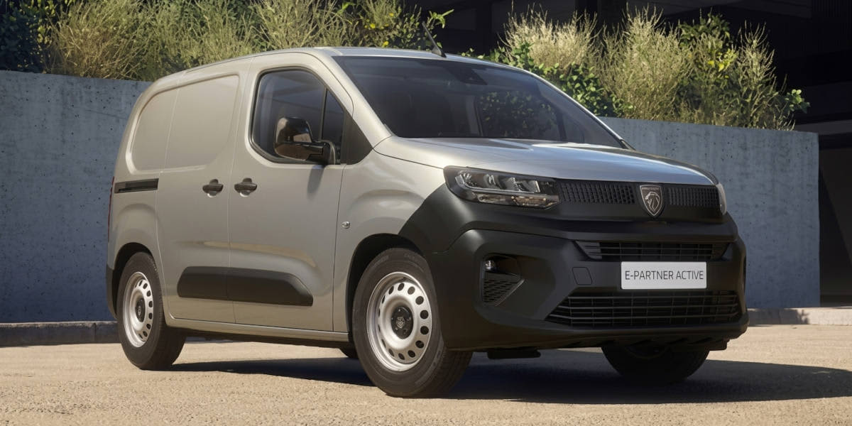 Ein silberner Peugeot E-Partner Active steht vor einer minimalistischen Betonkulisse. Prägend sind der unlackierte Stoßfänger, kompakte Scheinwerfer und das Wappen-Logo.   