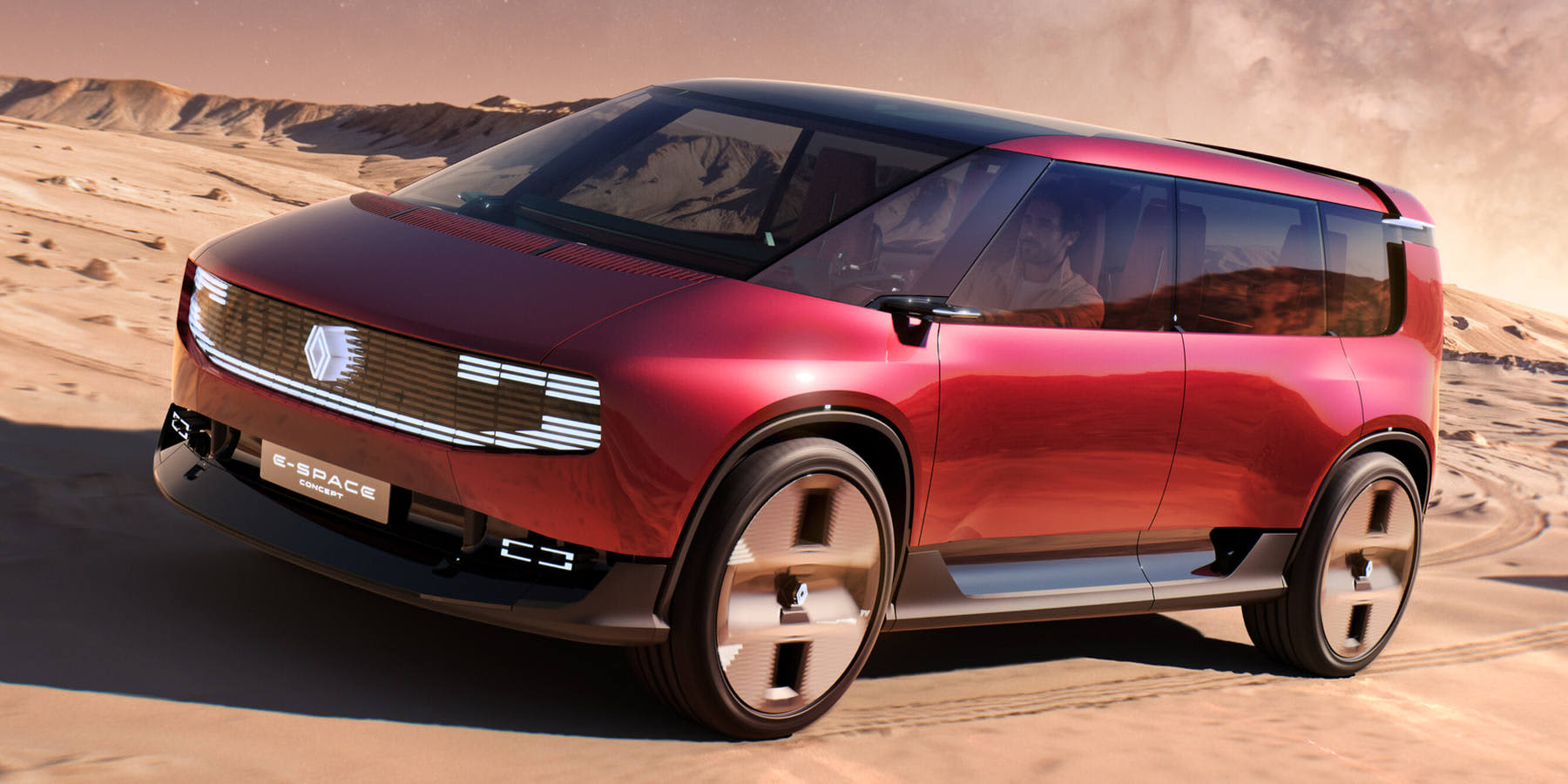 Ein rot-metallischer Renault E-Space Concept fährt durch eine Wüstenlandschaft. Prägend sind die beleuchtete Frontleiste und die futuristische Van-Silhouettte.   